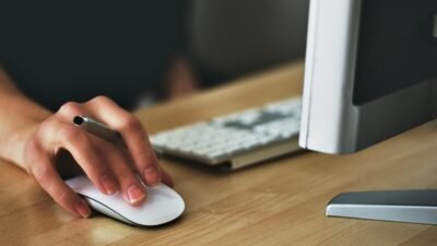Computador com uma mão mexendo o mouse Crédito: Pexels