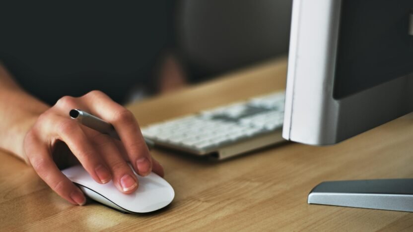 Computador com uma mão mexendo o mouse Crédito: Pexels